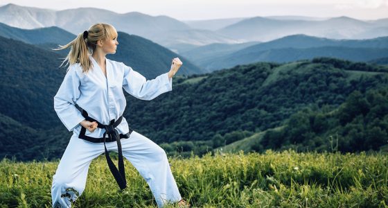 Young girl with a black belt performing martial arts in the mountains
