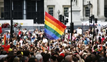 Pride Month celebrations in street with flag raised above crowd