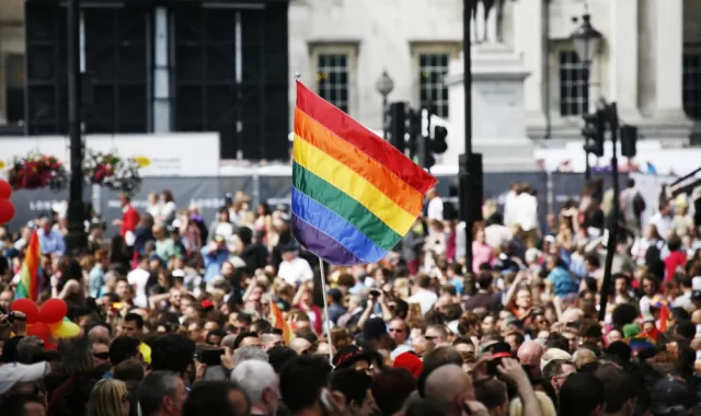 Pride Month celebrations in street with flag raised above crowd